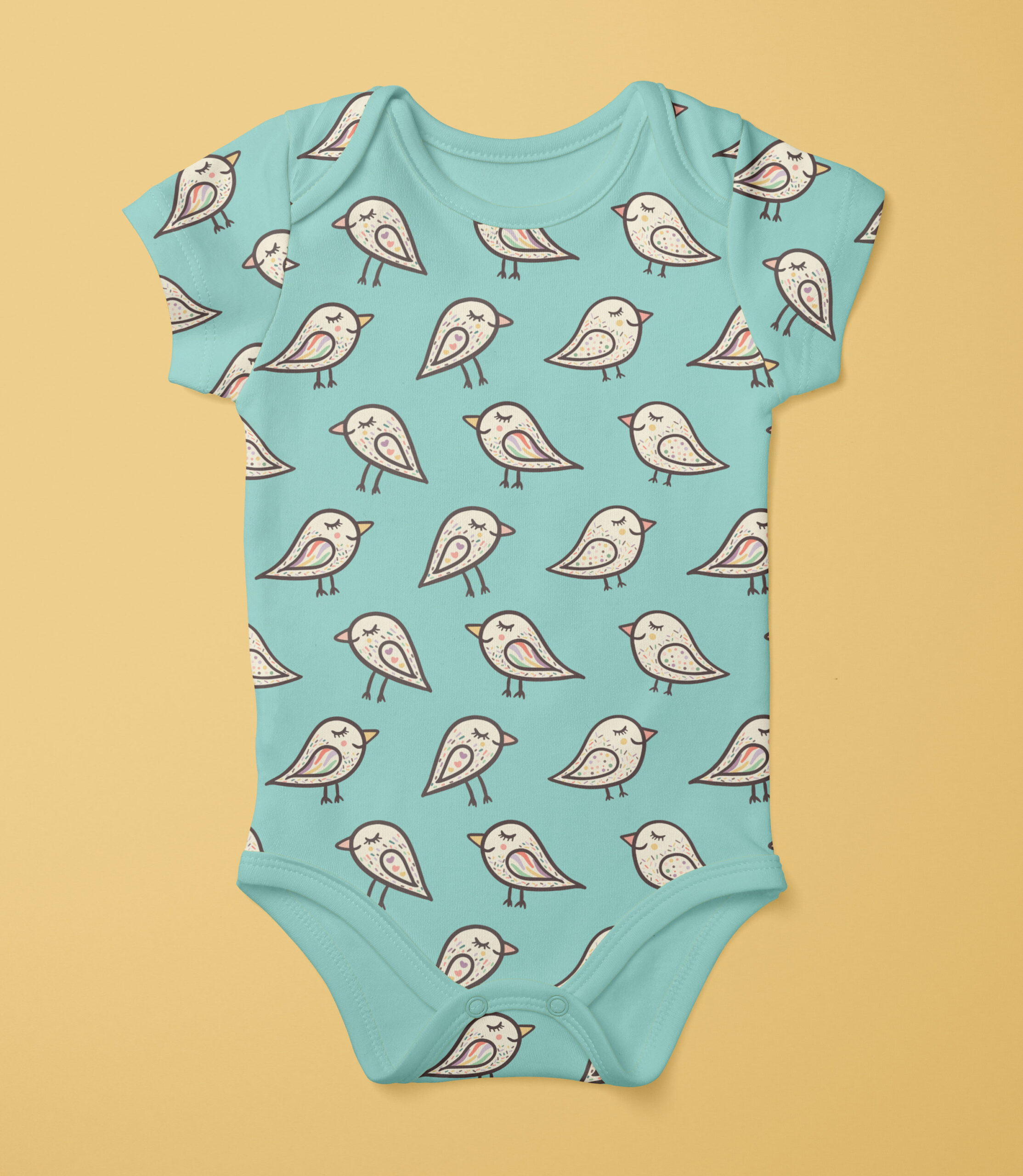 Babie onesie in a light pastel baby blue with handdrawn sleeping birds with dark outlines and fun patterns in muted rainbow colours on it. The onesie is on a warm pastel yellow background.