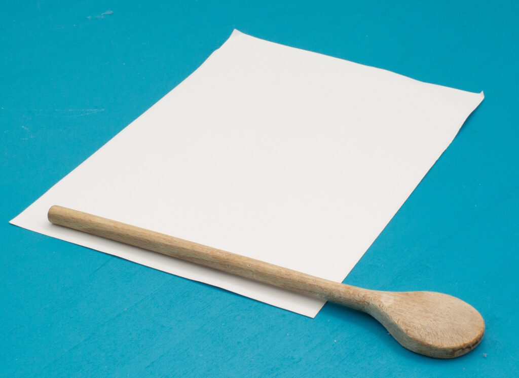 Sheet of paper and wooden spoon laying on a table