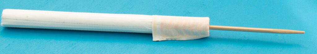 Paper roll in the fabric leg, chopstick partly inserted into the fabric and the paper tunnel