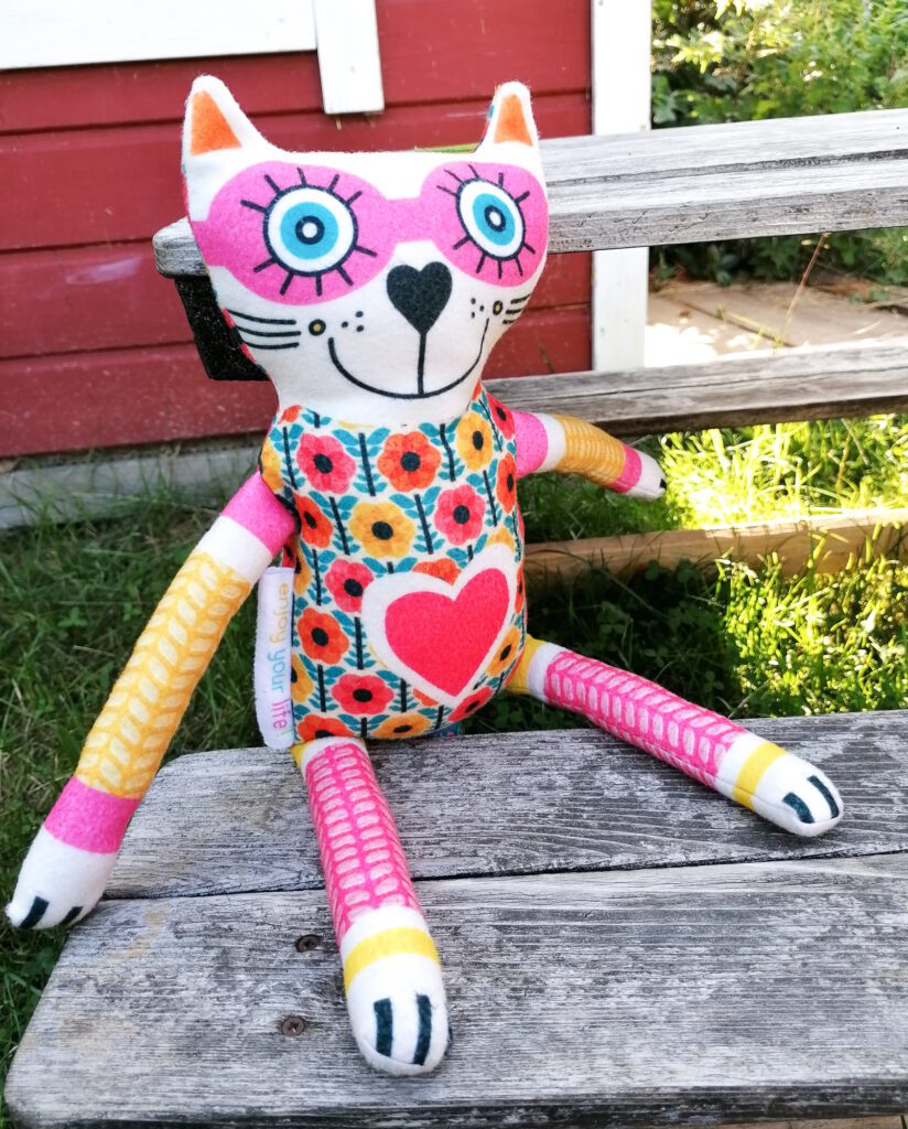 Completed "Crazy Cat Companion" sitting on a wooden bench in the garden.