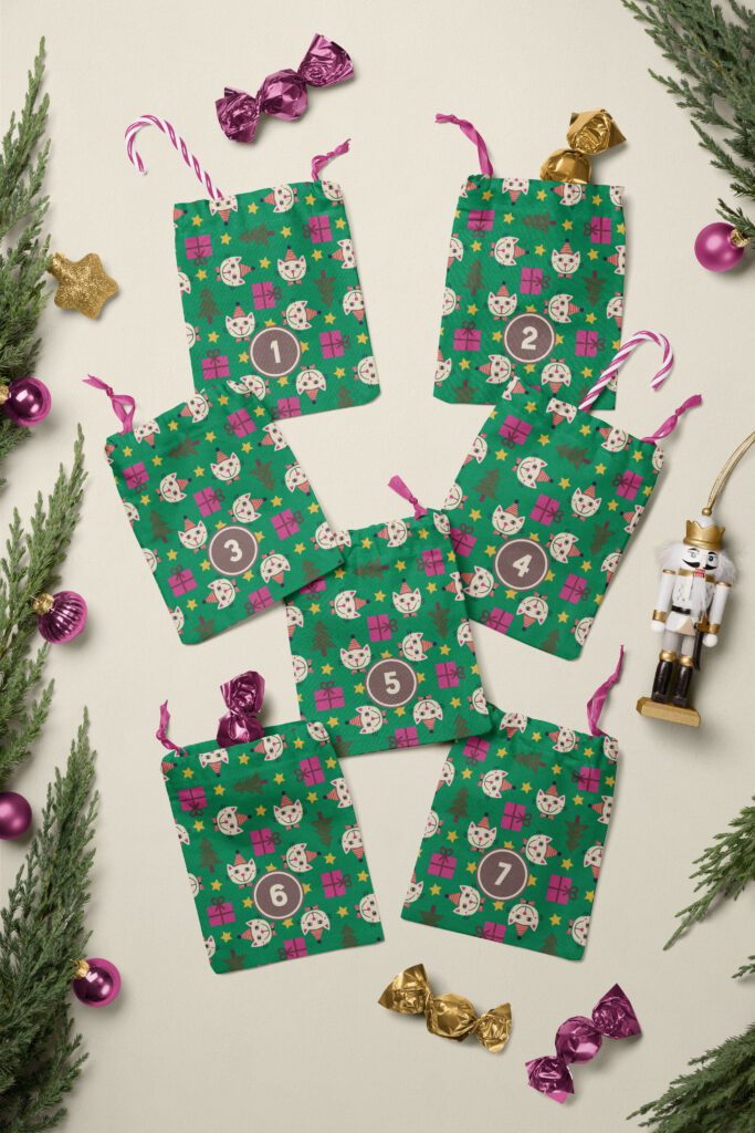 7 fabric Advent calendar bags with beige cats with party heads, pink purple Christmas gifts, xmas trees and yellow stars on jungle green. The bags lay on a beige white background that is decorated with tree branches, candy canes, a nutcracker, and pinkish purple Christmas baubles.