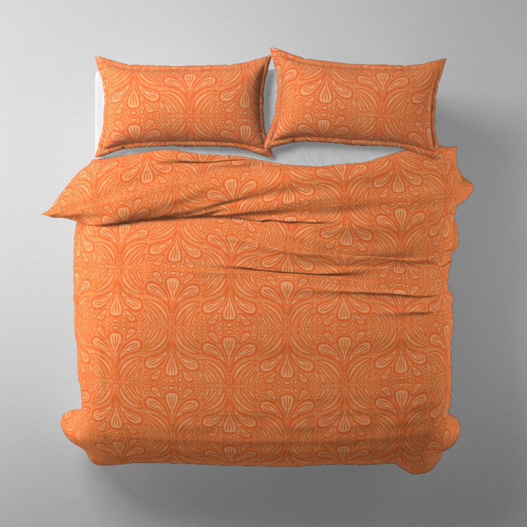 Orange duvet cover and pillows with a warm, heritage-inspired botanical pattern featuring symmetrical, block-print style shapes. The design evokes Arts & Crafts and William Morris aesthetics with a soft linen texture. The bedding is styled on a simple white bed frame in a neutral bedroom setting.