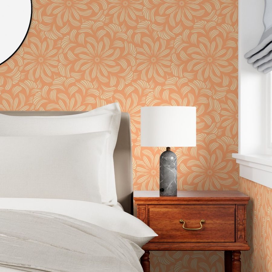 Peach floral wallpaper in cottagecore soft style with large stylized flowers on cream background. Shown in a bedroom setting with a wooden nightstand, gray stone lamp, white bedding, and soft natural light from window.