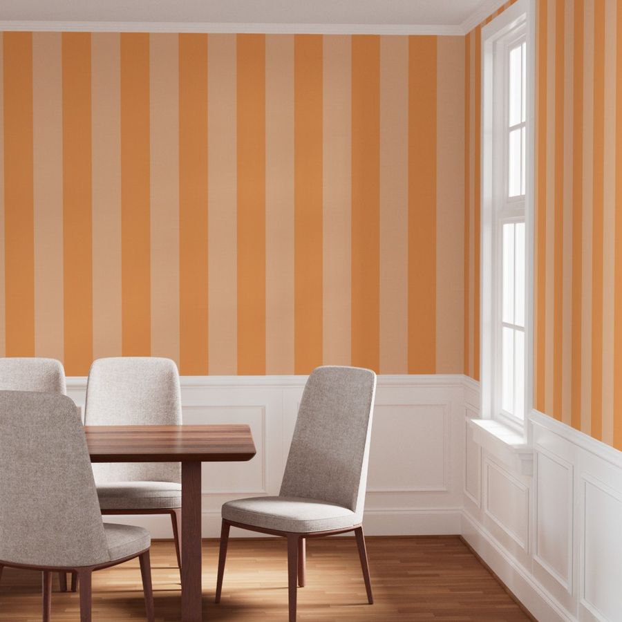 Dining room with apricot orange and soft peach bold vertical striped peel and stick wallpaper in a New Heritage style. The room features a wood dining table and gray upholstered chairs with white wainscoting and natural light from windows.