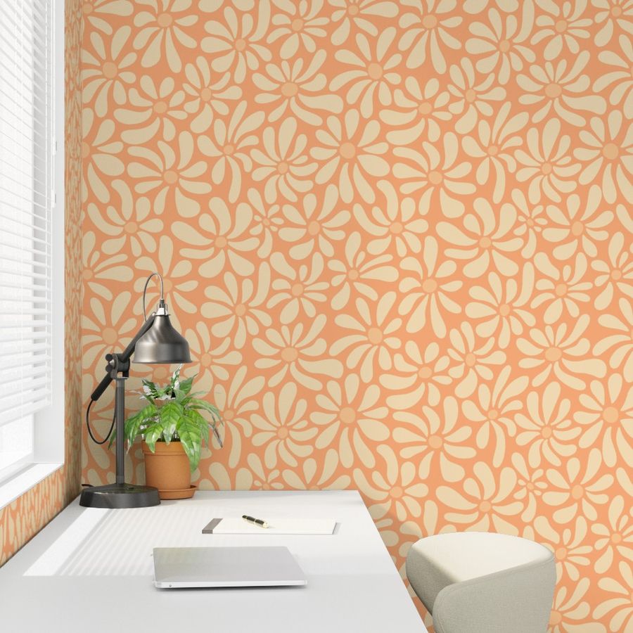 Wallpaper with a soft cream and pastel peach organic daisy flower pattern in a home office setting featuring a white desk, black adjustable lamp, potted green plant, and a cream-colored chair.