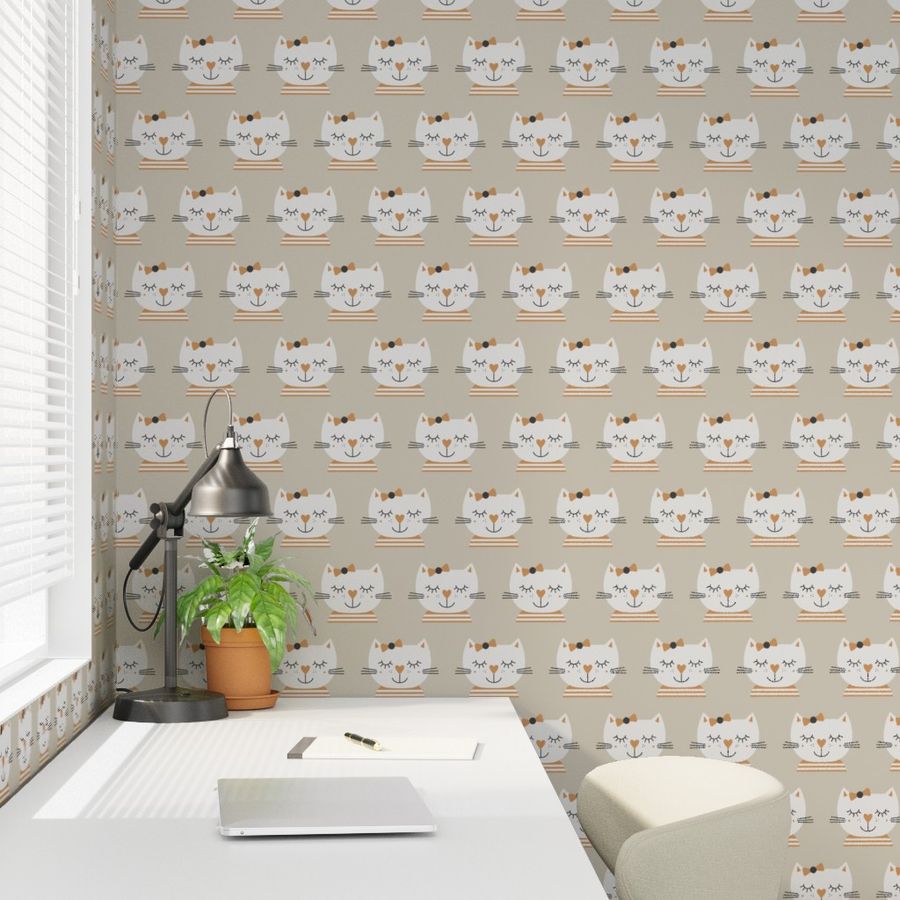 Photo showing a white desk in a kid's room with a wallpaper in the background. The wallpaper shows hand drawn beige sleeping cat girls on a warm brownish grey.