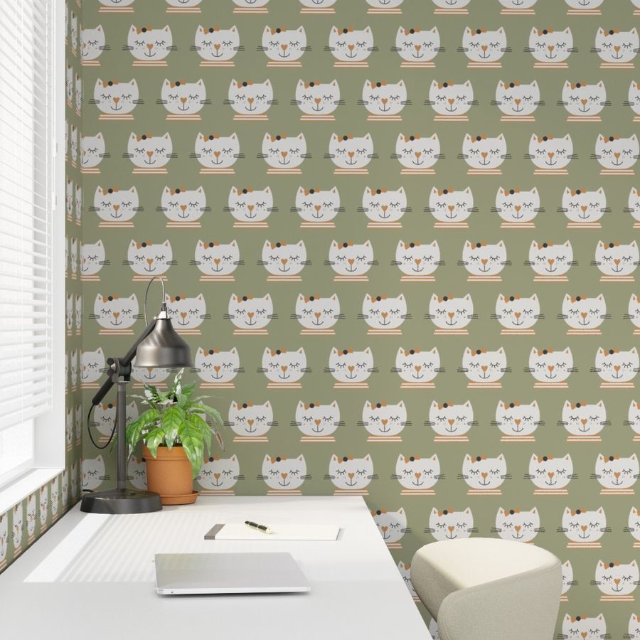 Photo showing a white desk in a kid's room with a wallpaper in the background. The wallpaper shows hand drawn beige sleeping cat girls on a sage grey green.
