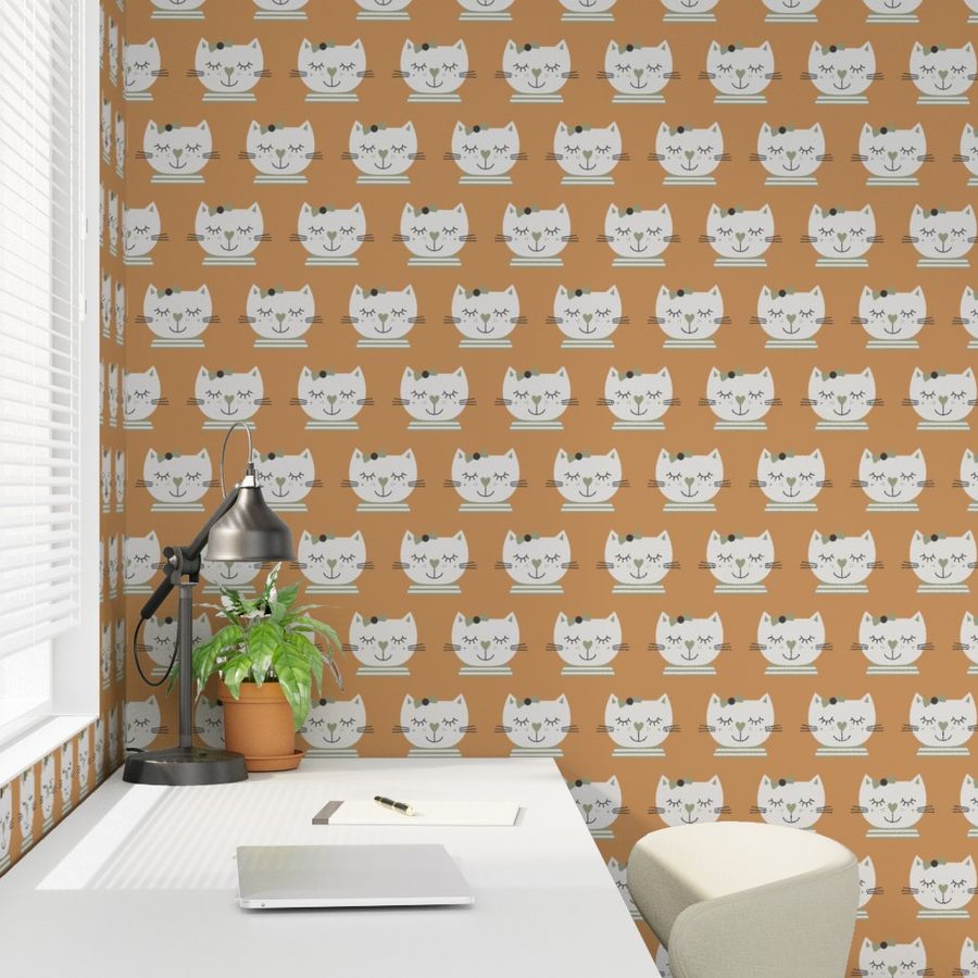 Photo showing a white desk in a kid's room with a wallpaper in the background. The wallpaper shows hand drawn beige sleeping cat girls on a warm fudge brown.