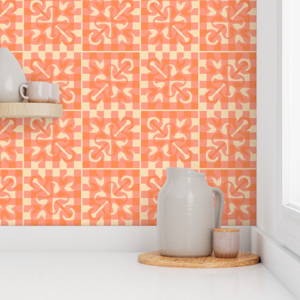 Warm pink and orange textured tile style wallpaper in a kitchen setting, featuring a geometric pattern with floral-inspired shapes. The wallpaper coordinates with modern kitchen accessories including a ceramic pitcher, cup, wooden tray, and floating shelf.